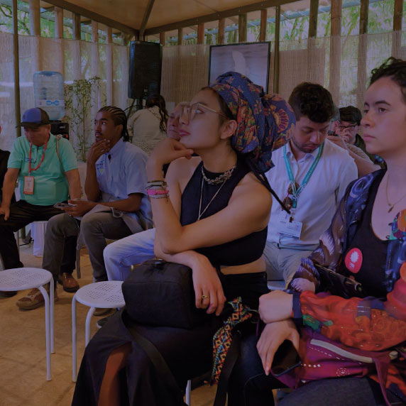 Personas asistiendo a un evento mujer en primer plano con mano en el menton excuchando con atención