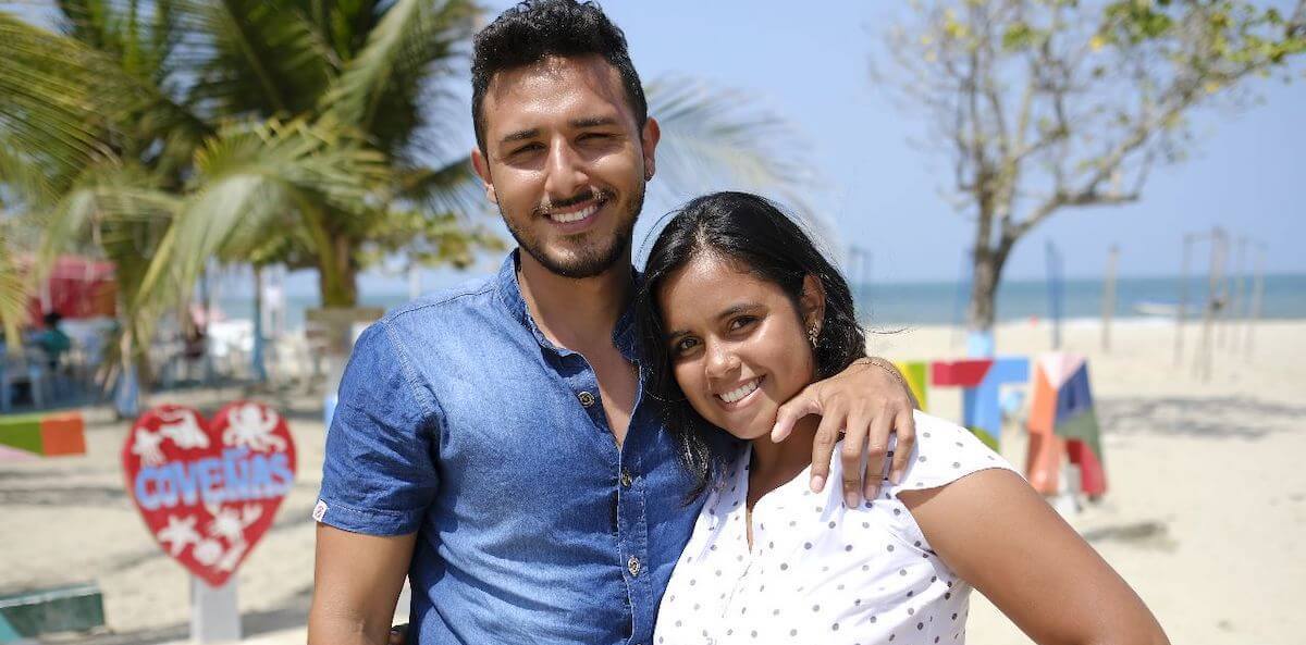 Foto de una pareja joven (mujer y hombre) en una playa sonriendo