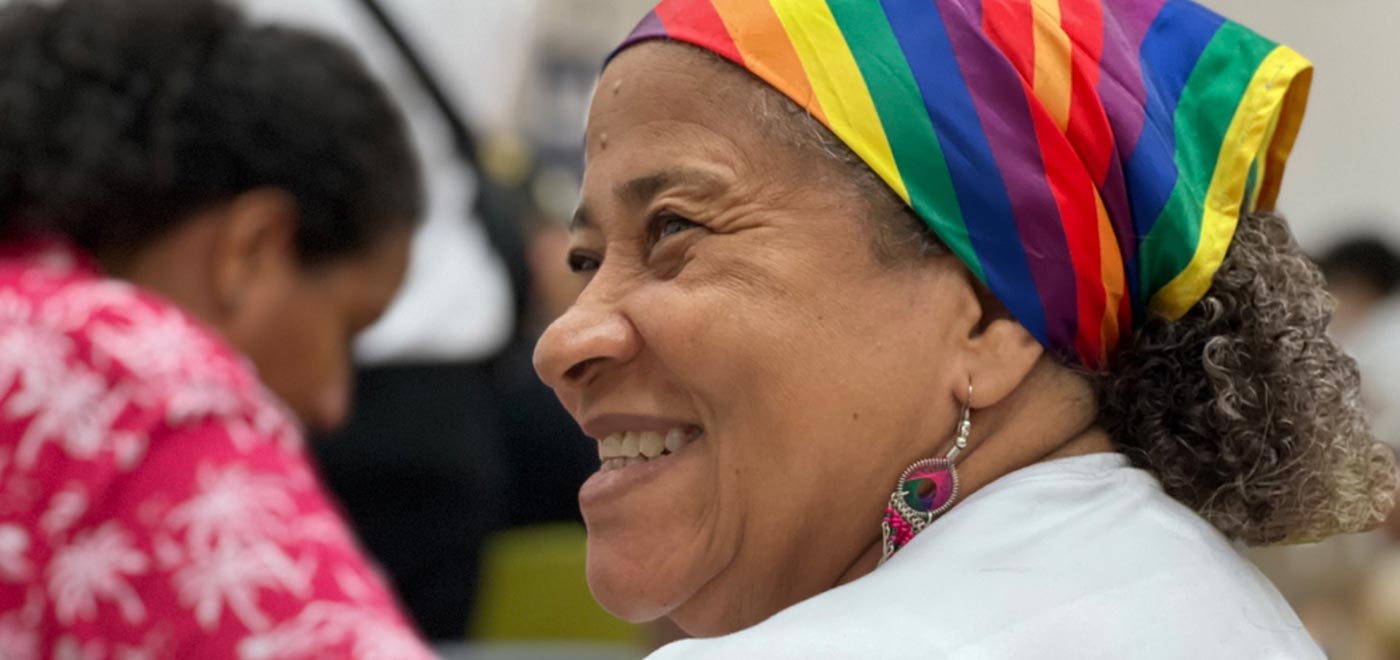 Mujer sonriendo con pañoleta de los colores LGBTIQ+