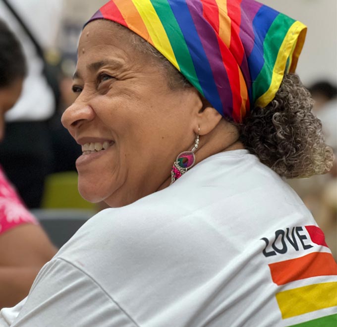 Mujer sonriendo con pañoleta de los colores LGBTIQ+