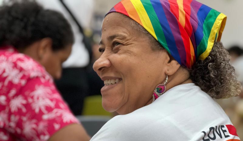 Mujer sonriendo con pañoleta con los colores de la bandera LGBTIQ+, 