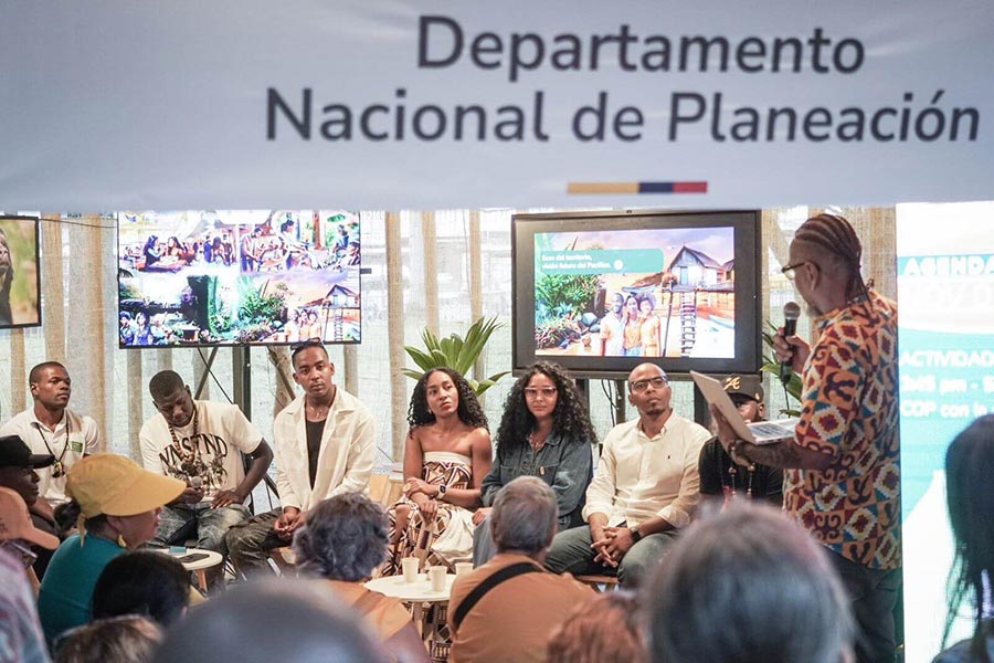 Conferencista hablando a un público dentro del estand del DNP en la COP16