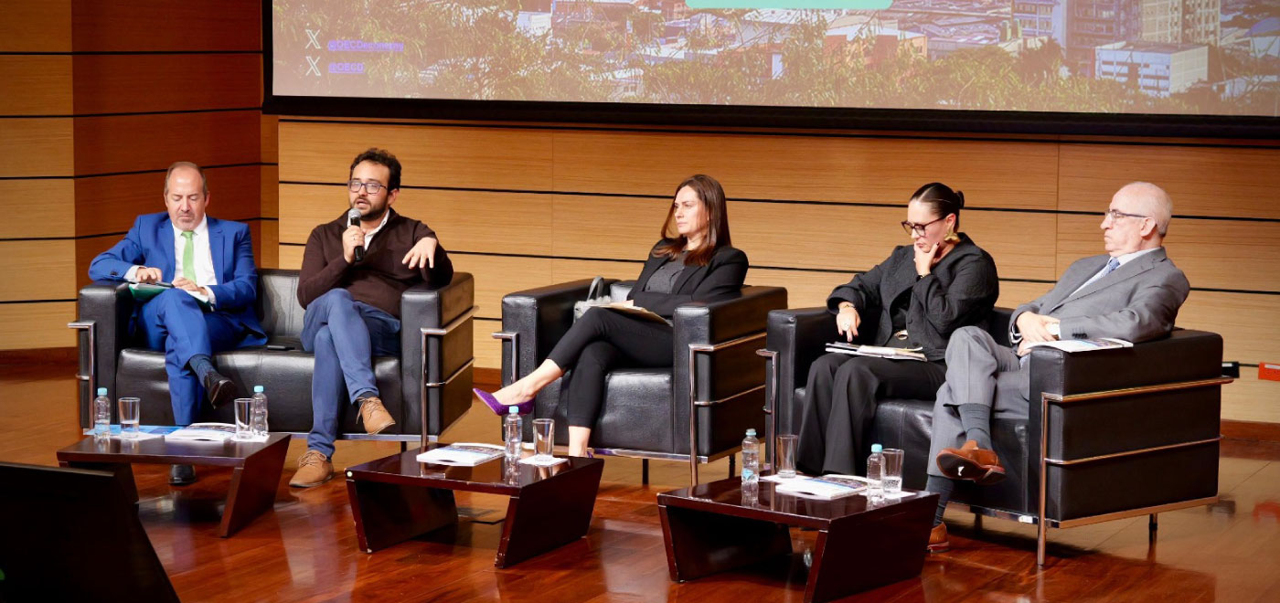 Cinco personas en mesa de trabajo  hablan sobre la  macroeconómica y la inversión social en Colombia