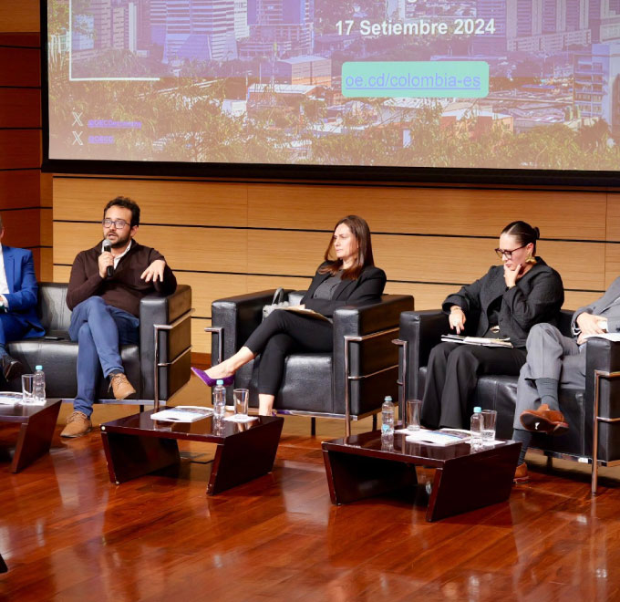 Cinco personas en mesa de trabajo  hablan sobre la  macroeconómica y la inversión social en Colombia