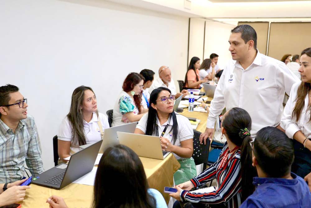 Director del Sistema General de Regalías hablando con personas en una reunión de trabajo